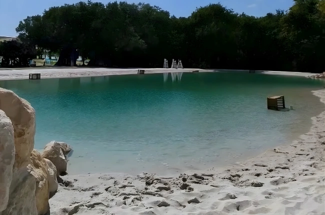 A completed Clair Lagon lagoon in a sun-drenched Mediterranean setting with turquoise water and sandy beach