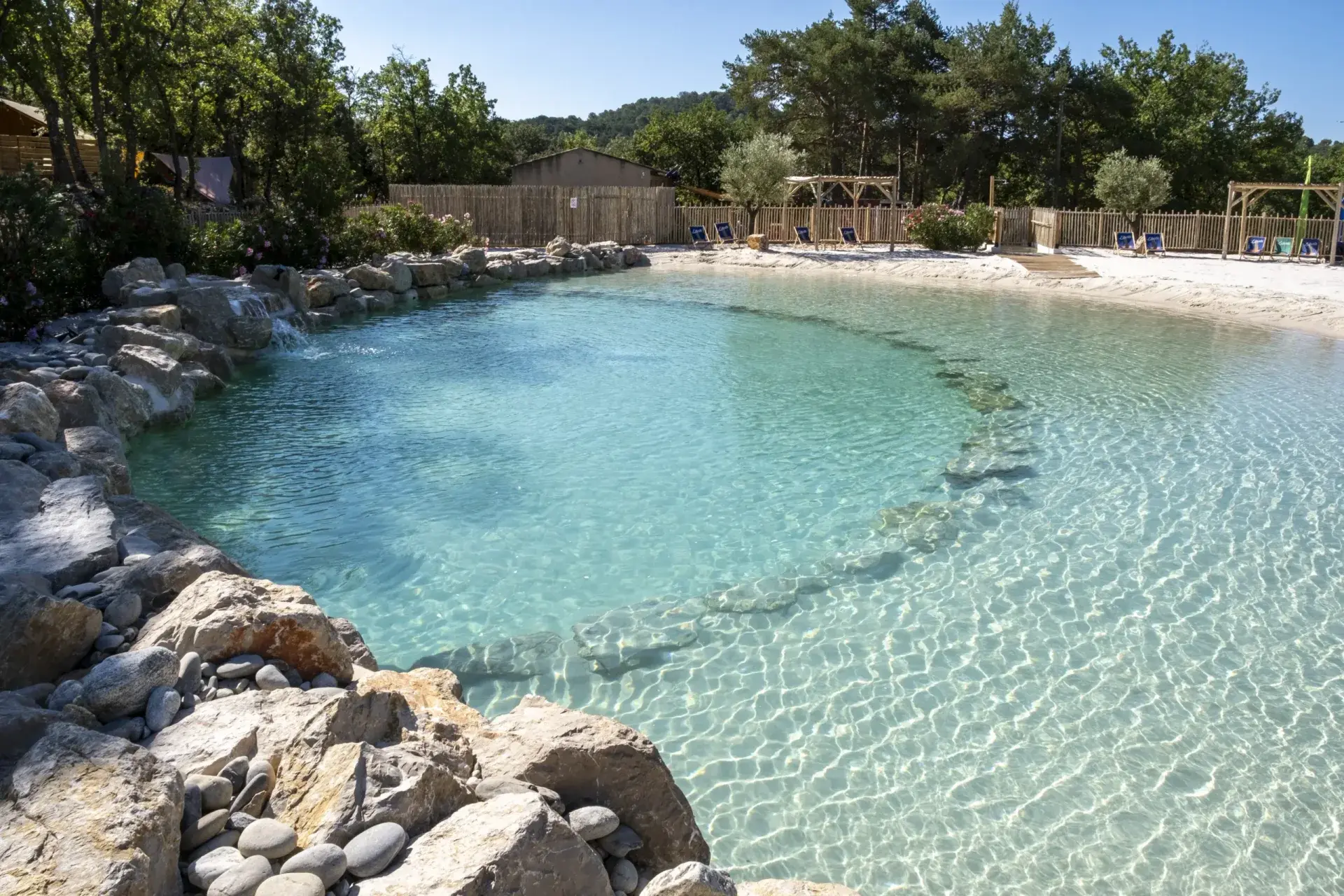 Natural fine-sand lagoon with turquoise freshwater and warm sandy beach entry, a completed Clair Lagon installation