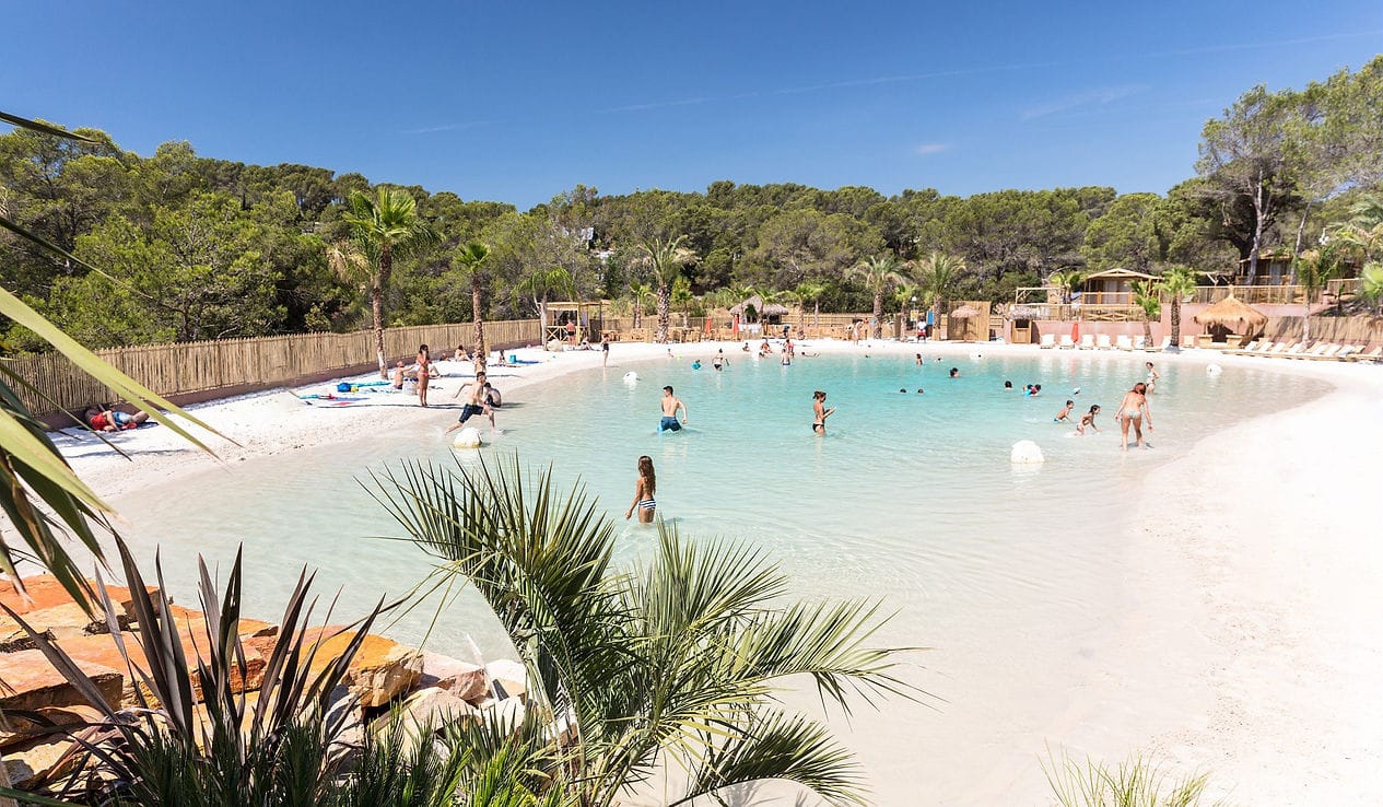 A commercial-scale natural lagoon set in a resort-style property, turquoise water with a beach entry